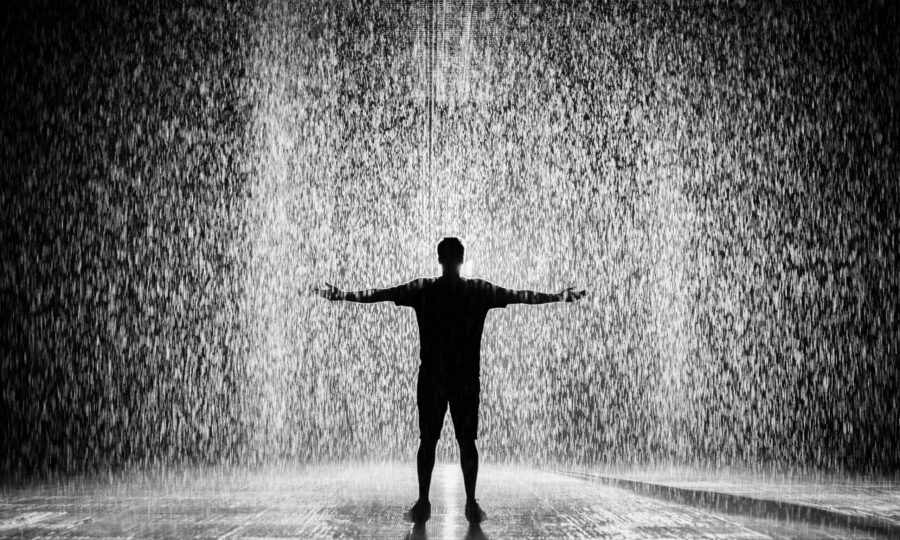 Silhouetted figure standing with arms outstretched in heavy rain