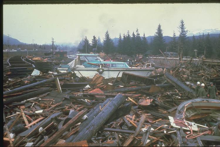 Tsunami damage to the north end of Resurrection Bay near Seward. The first wave arose after a waterfront and submarine slump developed within minutes of the beginning of the earthquake. A large mound of water rose in the fiord. This wave and other waves washed into the town of Seward destroying buildings, docks, railroad facilities, and small boats. About twenty minutes later the first wave from the major tsunami arrived. The maximum runup was between 30 and 38 feet (9.1 -11.5 m) above mean low water. Waves continued for more than eight hours after the quake. (Source: NOAA/NCEI, US DOI)