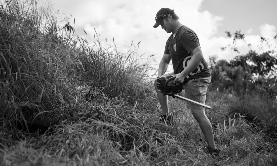 Person clearing brush with a string trimmer on a steep slope