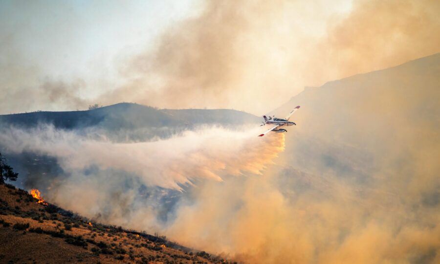 Air tanker dropping retardant along a burning hillside